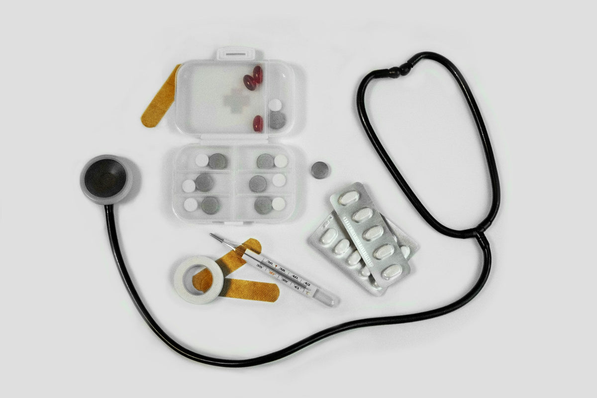 First aid supplies including bandages, medicine and a stethoscope laid out on a white surface