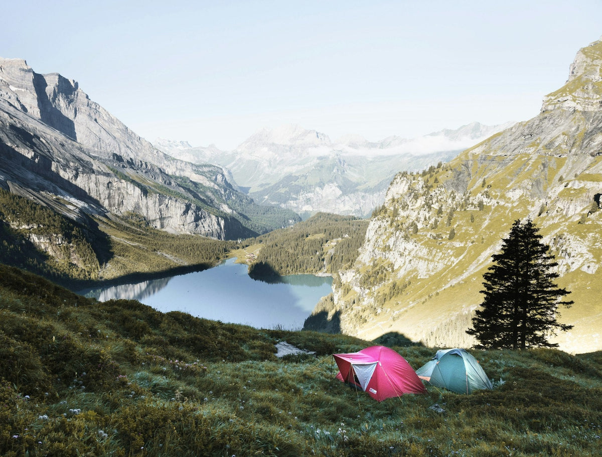 Tents beside a clear alpine lake in a mountain valley