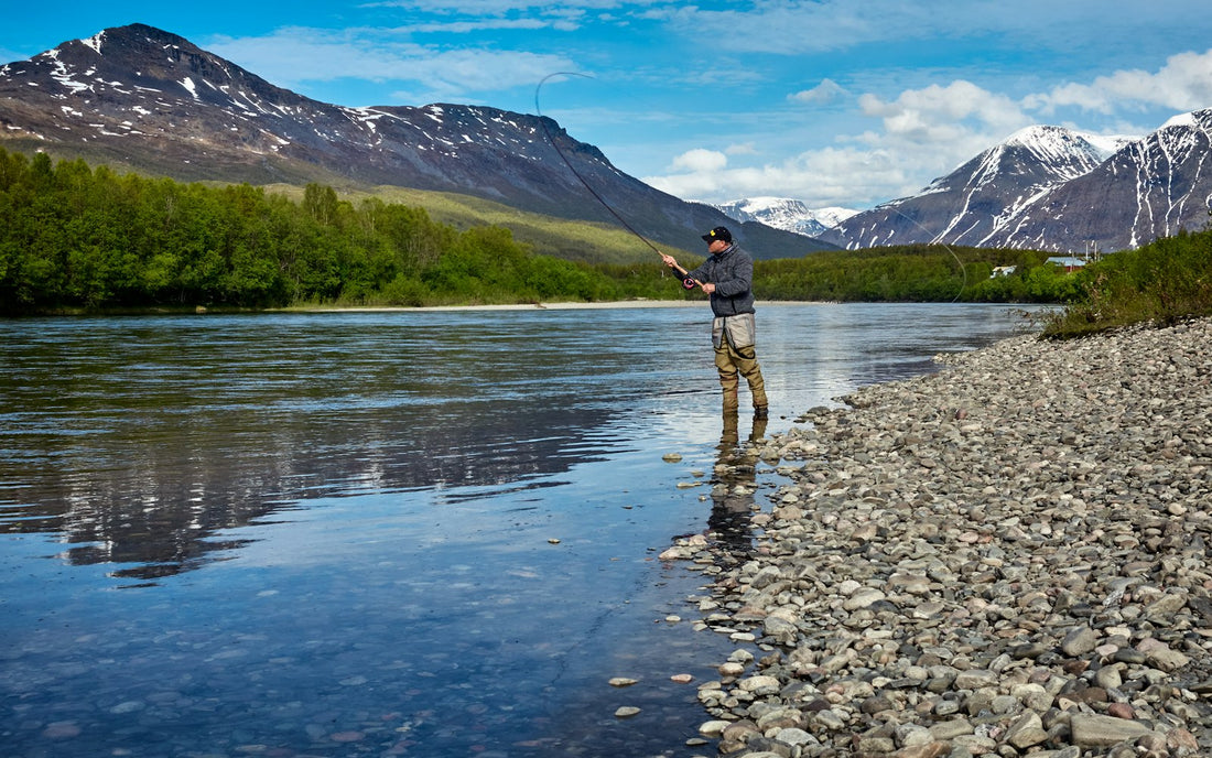 Angler standing on the shore of a calm mountain lake