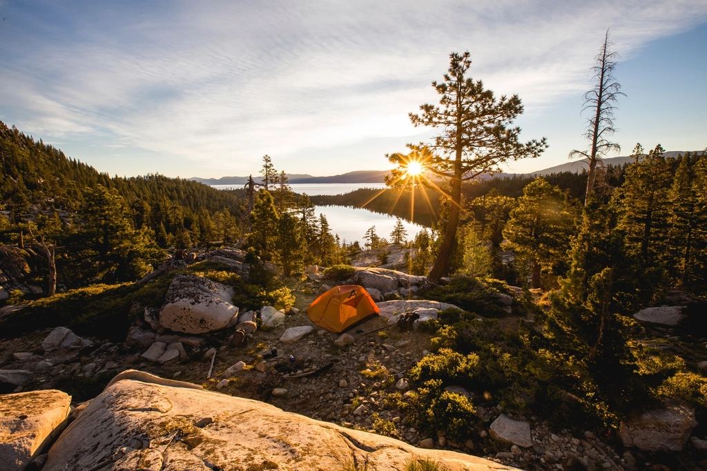 Tent pitched above an alpine lake at sunrise